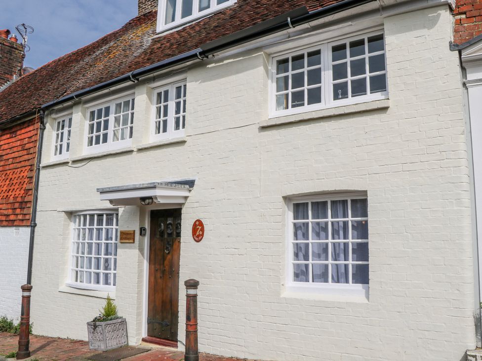 A white house with a wooden door and multiple windows at 7 Chapel Hill Quinc Cottage in Lewes
