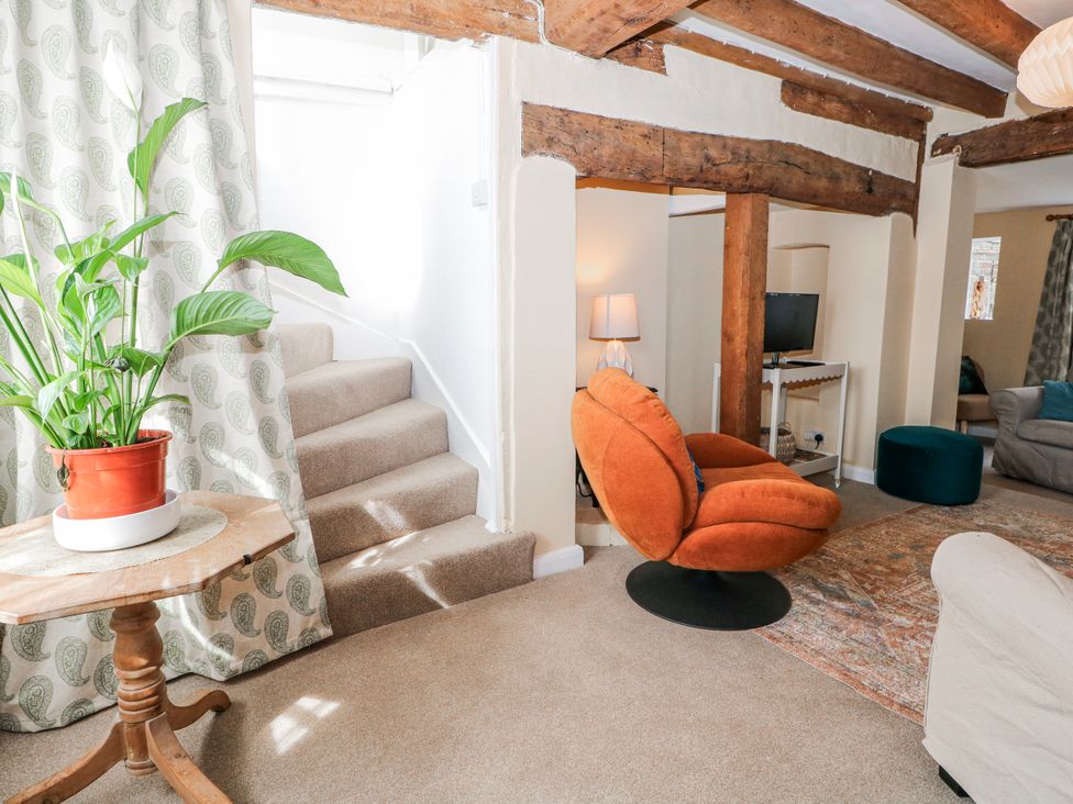 A living room with a staircase and furniture at 7 Chapel Hill Quinc Cottage Lewes