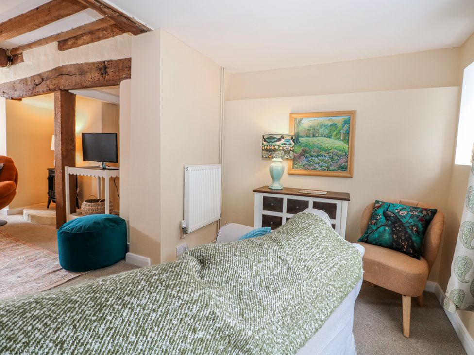 A bedroom with a bed, television, chair, and table at 7 Chapel Hill Quinc Cottage in Lewes