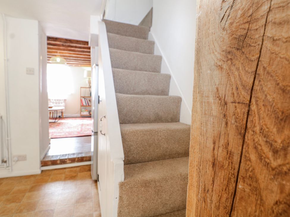 A staircase with carpet and a wall at 7 Chapel Hill Quinc Cottage in Lewes