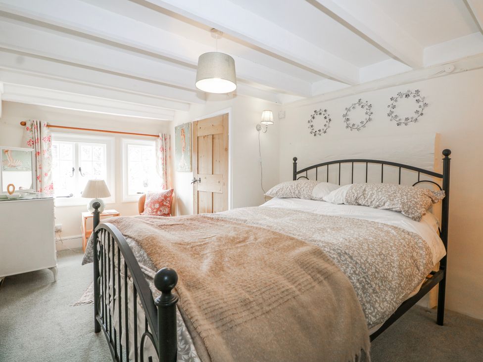 A bedroom with a bed and windows at 7 Chapel Hill Quinc Cottage in Lewes