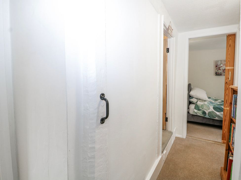 A hallway with a door leading to a bedroom and a bookshelf at 7 Chapel Hill Quinc Cottage Lewes