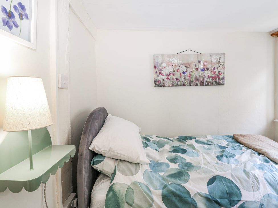A bedroom with a bed and a table lamp at 7 Chapel Hill Quinc Cottage Lewes