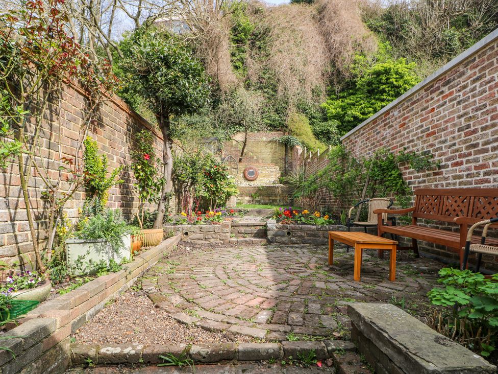 A garden with a paved area, flowers, and seating at 7 Chapel Hill Quinc Cottage Lewes