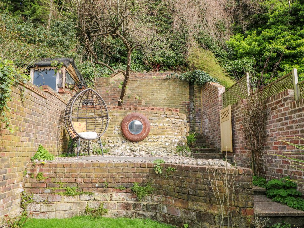 A garden with a hanging chair and brick walls at 7 Chapel Hill Quinc Cottage Lewes