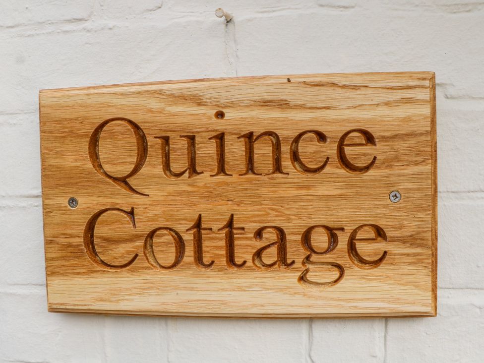 A wooden sign displaying the name Quince Cottage in Lewes
