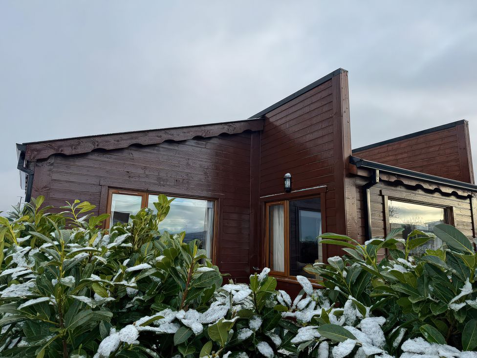 A wooden house with snow-covered shrubs at No 3