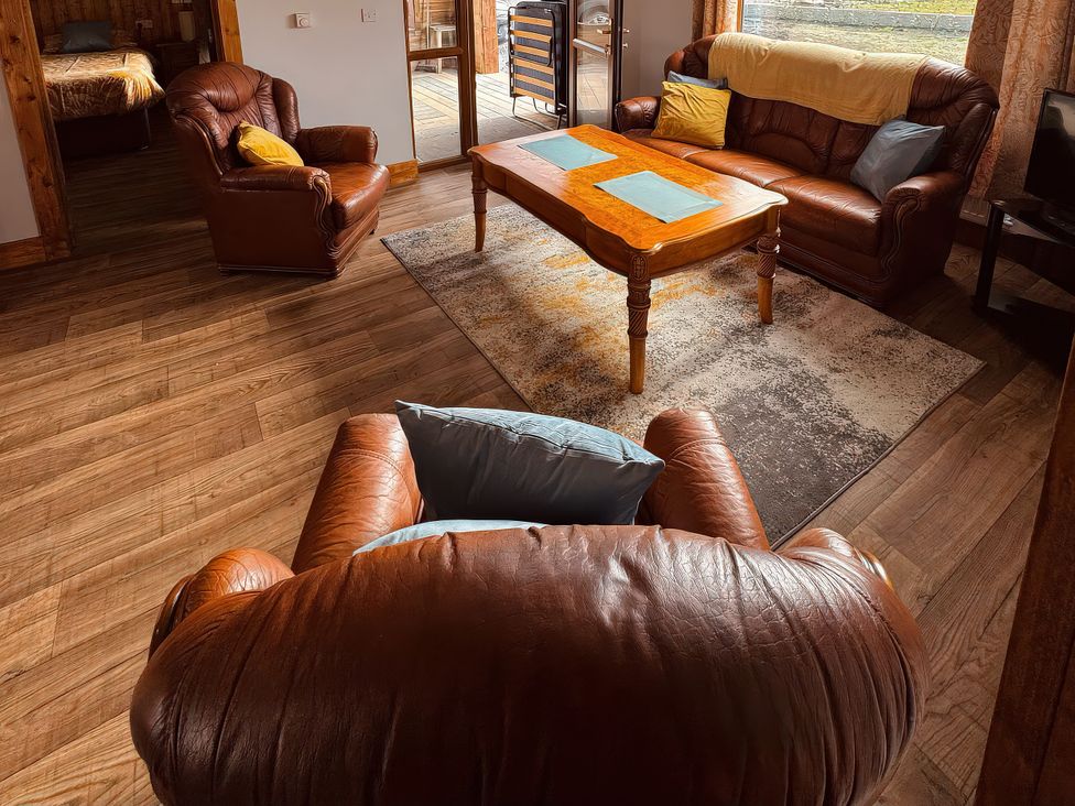A living room with leather furniture and a table at Fisherman Lodge No 2 Enniskillen