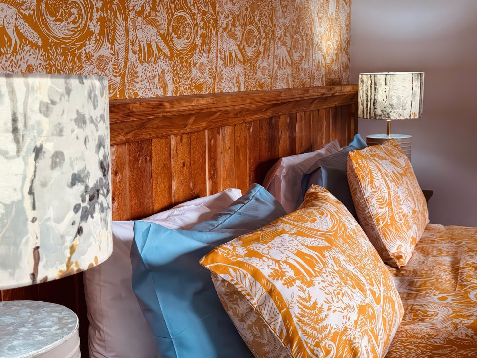 A bedroom with a wooden headboard and colorful bedding at Fisherman Lodge No 2 Enniskillen
