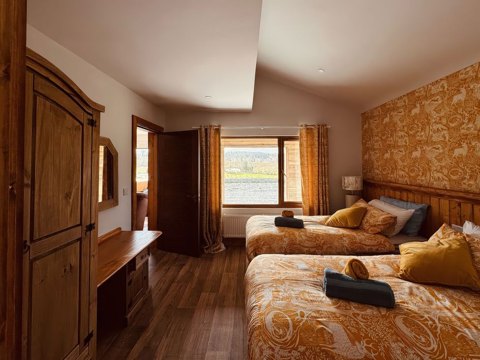 A bedroom with two beds and a wardrobe at Fisherman Lodge No 2 Enniskillen