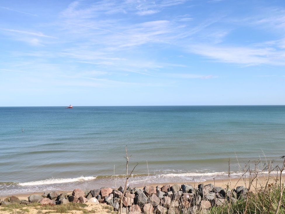 A view of the ocean with a boat in the distance and rocks at the shore