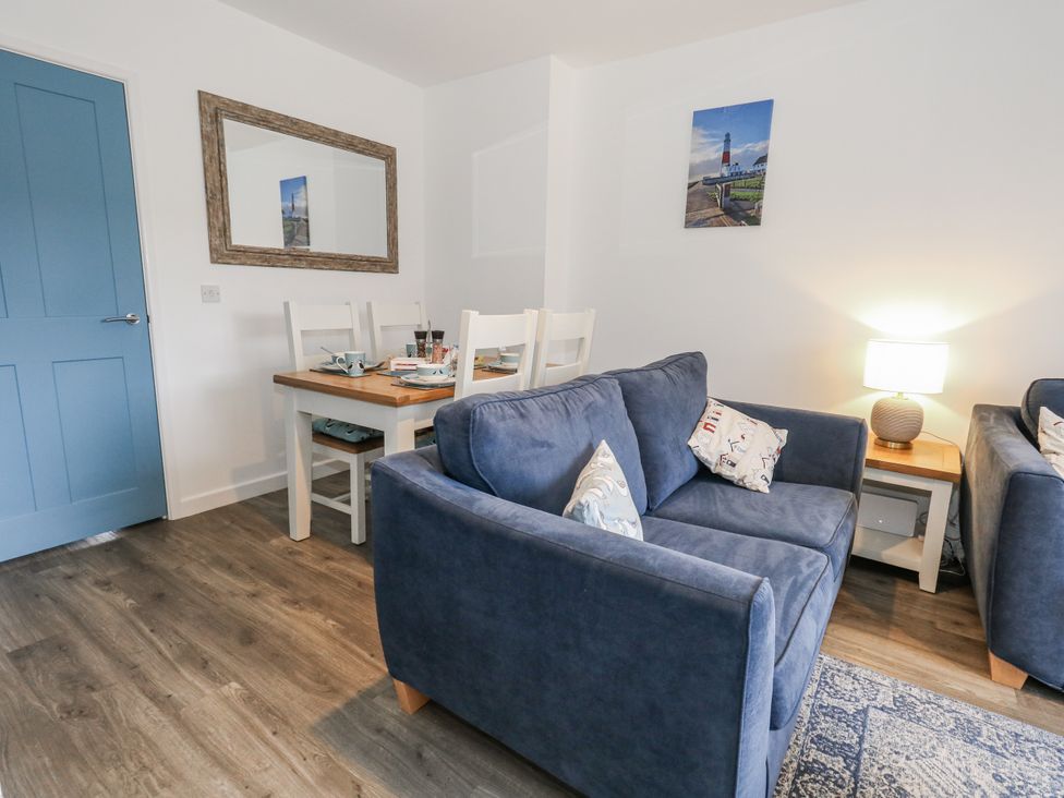 A living room with a sofa and dining area at 8 Park View Grove Weymouth