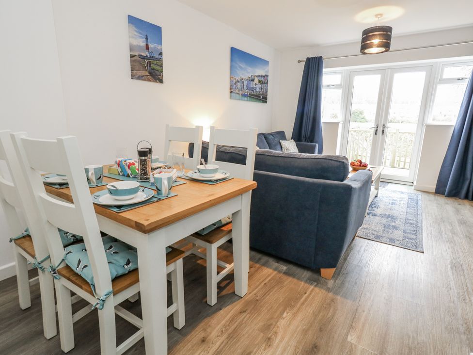 A dining area with a table set and a sofa at 8 Park View Grove Weymouth