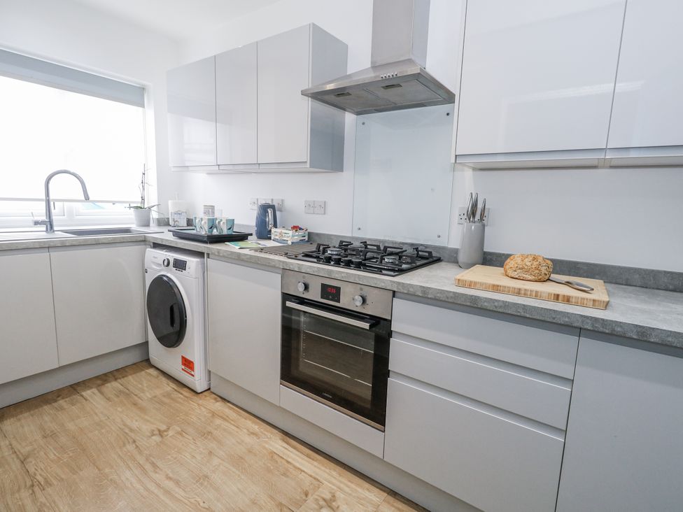 A kitchen with sink, washing machine, oven, and gas stove at 8 Park View Grove in Weymouth