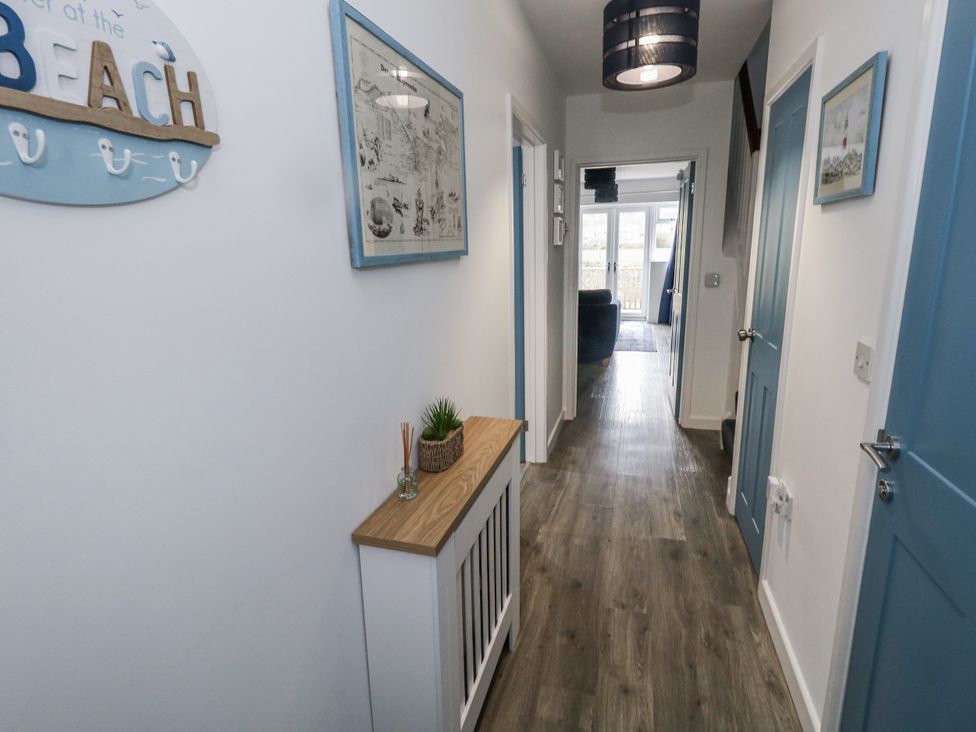 A hallway with blue doors and a plant on a console table at 8 Park View Grove in Weymouth
