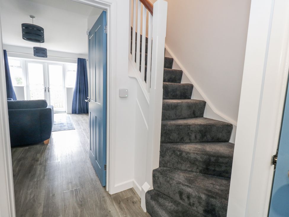 A hallway with a staircase and a view into a living room at 8 Park View Grove, Weymouth