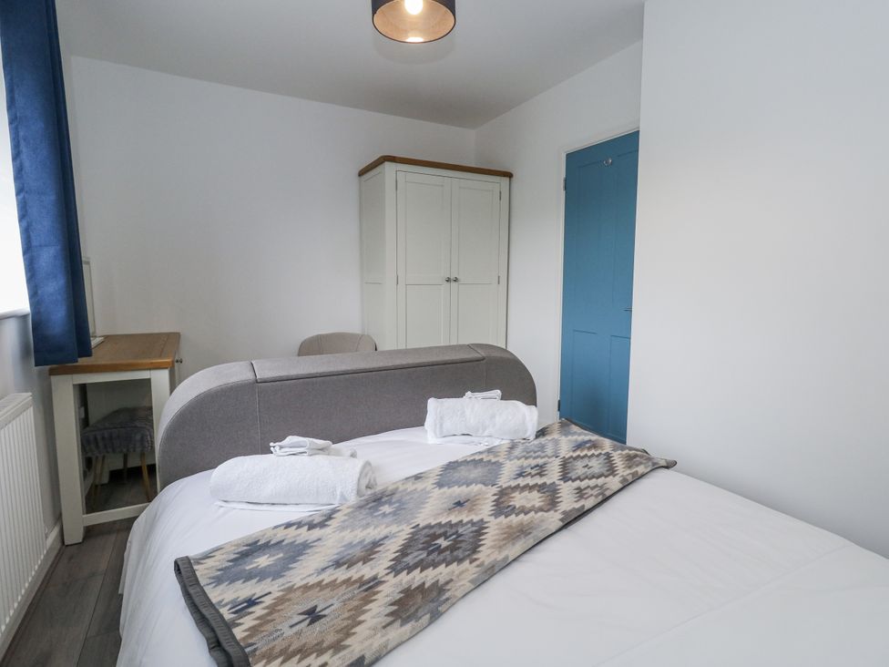 A bedroom with a bed, blanket, and wardrobe at 8 Park View Grove in Weymouth