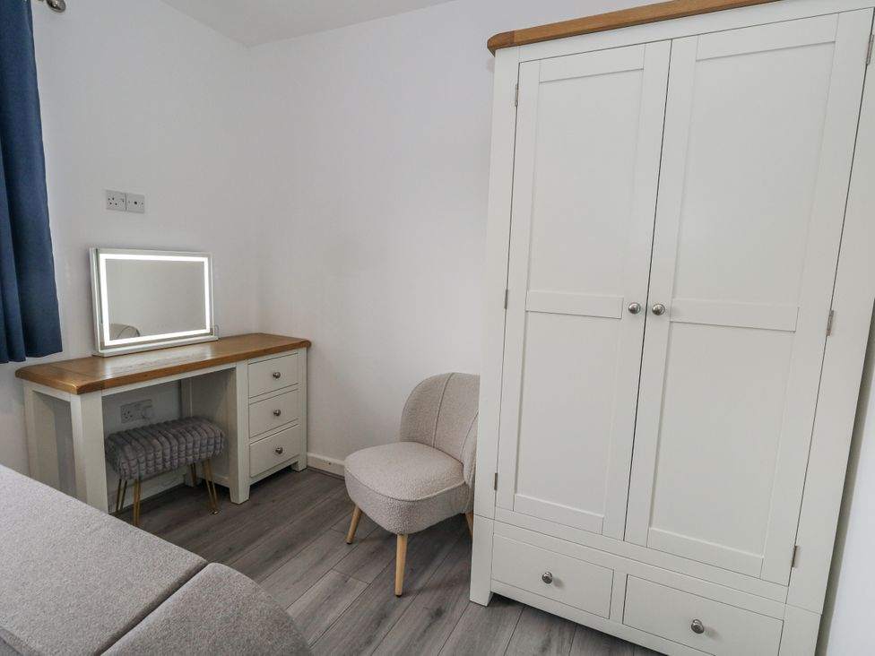 A bedroom with wardrobe, mirror, and vanity desk at 8 Park View Grove in Weymouth