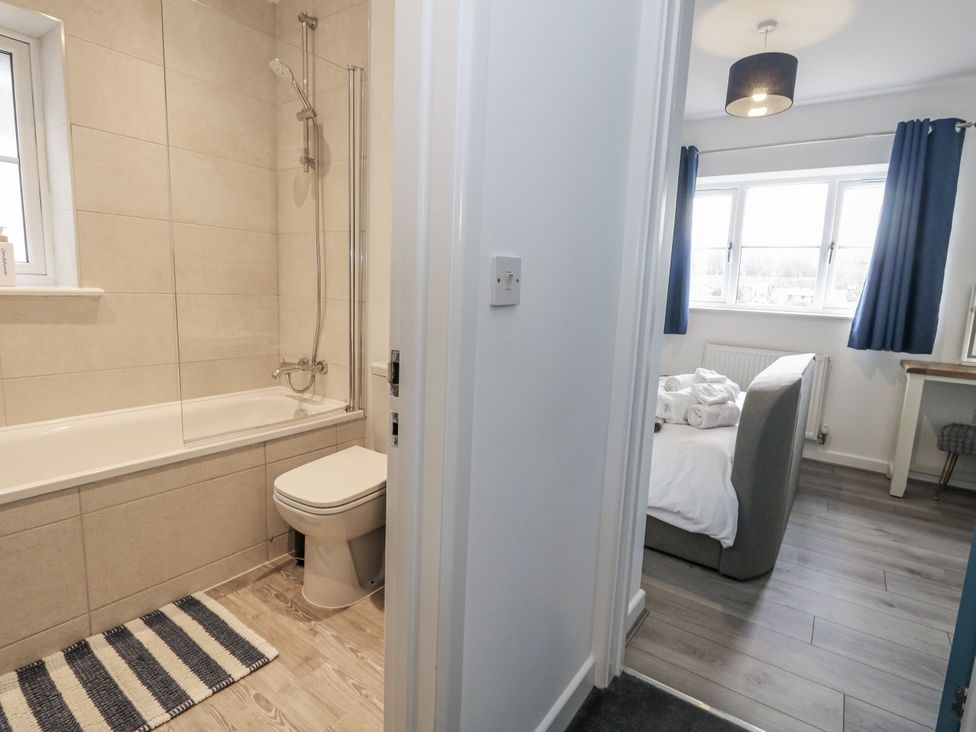 A bathroom with a bathtub and a bedroom with a couch at 8 Park View Grove in Weymouth