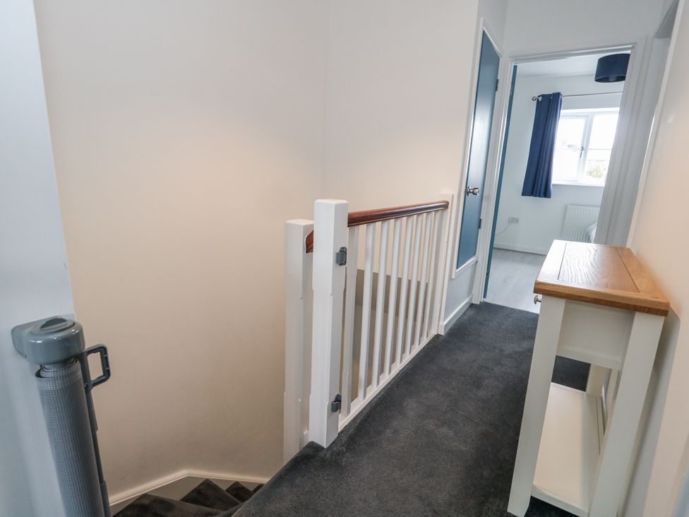 A hallway with a staircase and console table at 8 Park View Grove in Weymouth