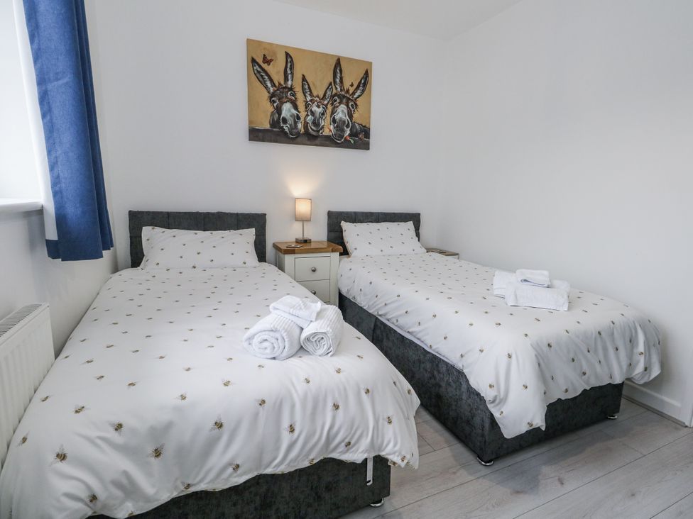 A bedroom with two beds and a painting at 8 Park View Grove in Weymouth