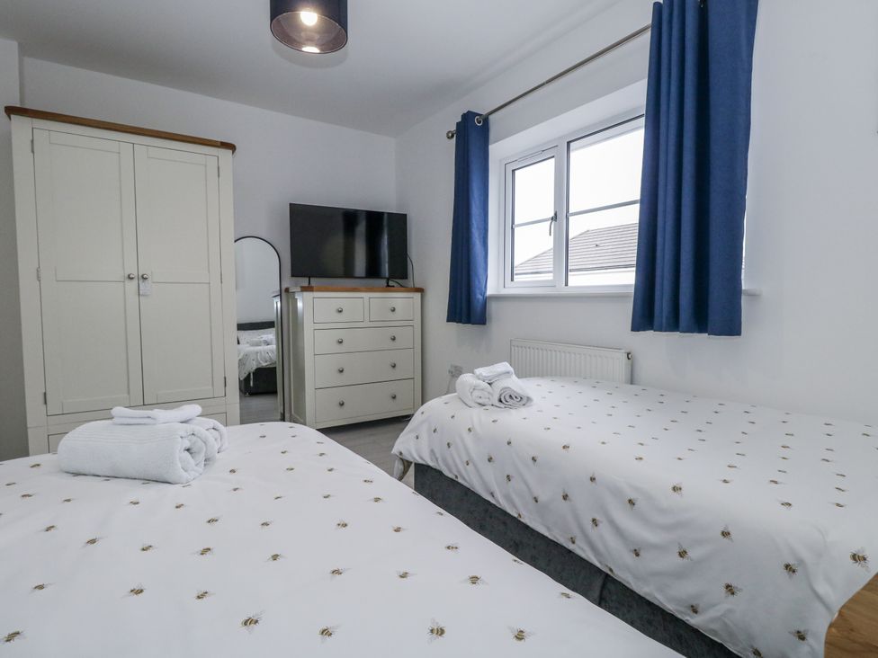 A bedroom with two beds and a television at 8 Park View Grove in Weymouth