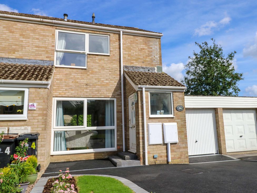 A house with a garage and flowers at Camellia Cottage in Wimborne Minster