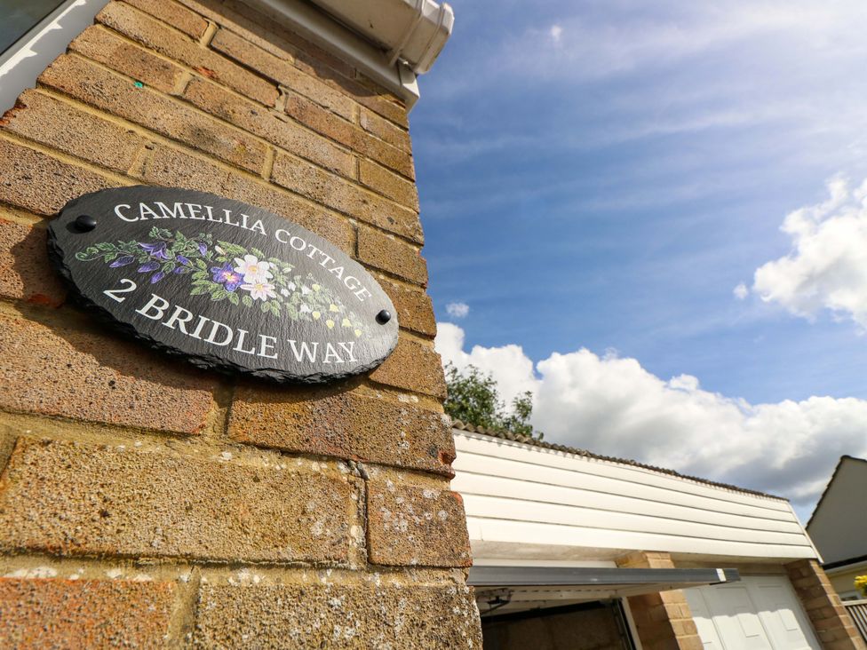 A nameplate on a brick wall at Camellia Cottage in Wimborne Minster