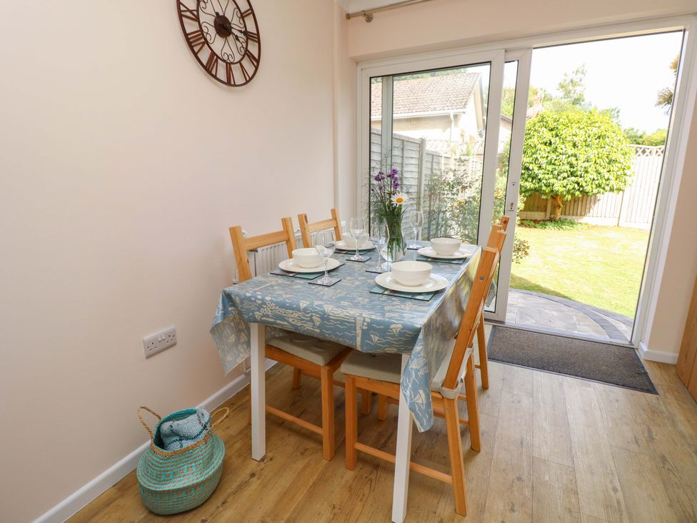 A dining room with a table set for meals at Camellia Cottage in Wimborne Minster