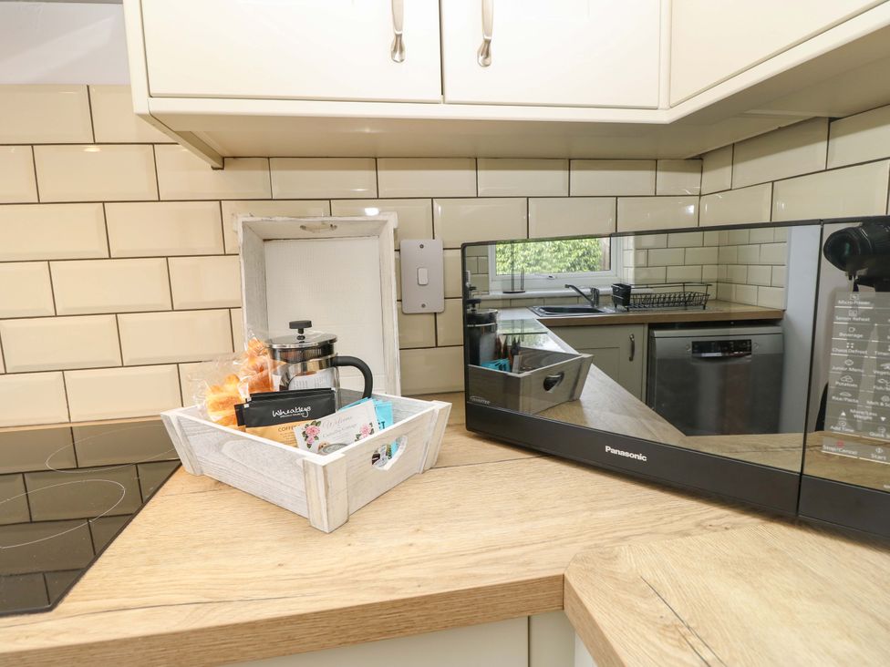 A kitchen with a microwave and coffee items at Camellia Cottage in Wimborne Minster