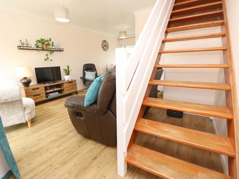A living room with a staircase and sofa at Camellia Cottage in Wimborne Minster