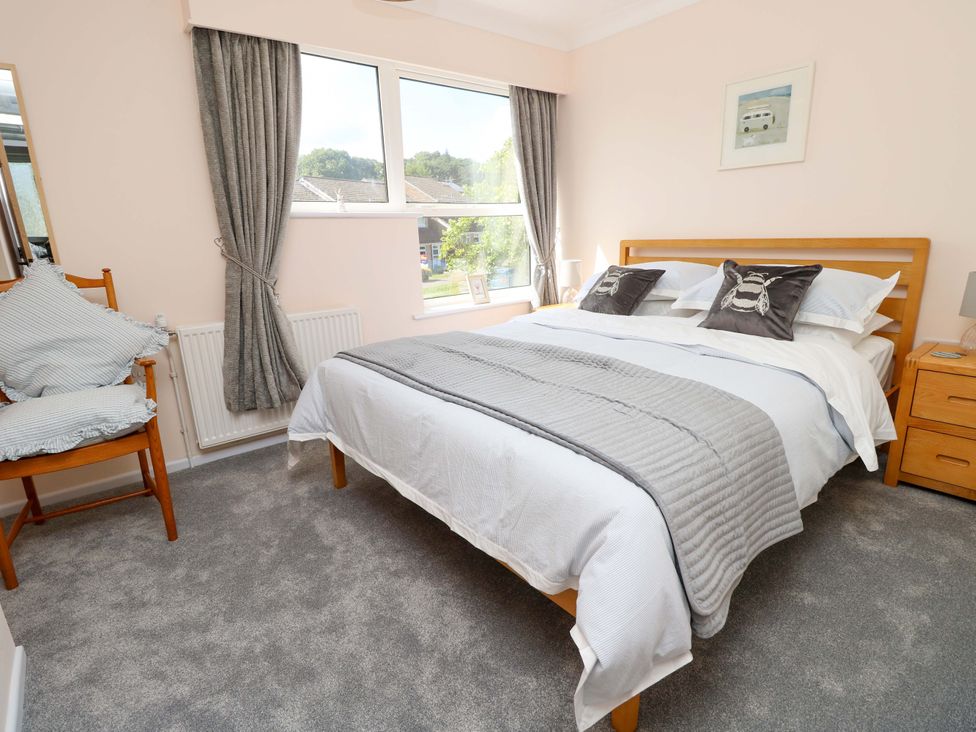 A bedroom with a bed and armchair at Camellia Cottage in Wimborne Minster