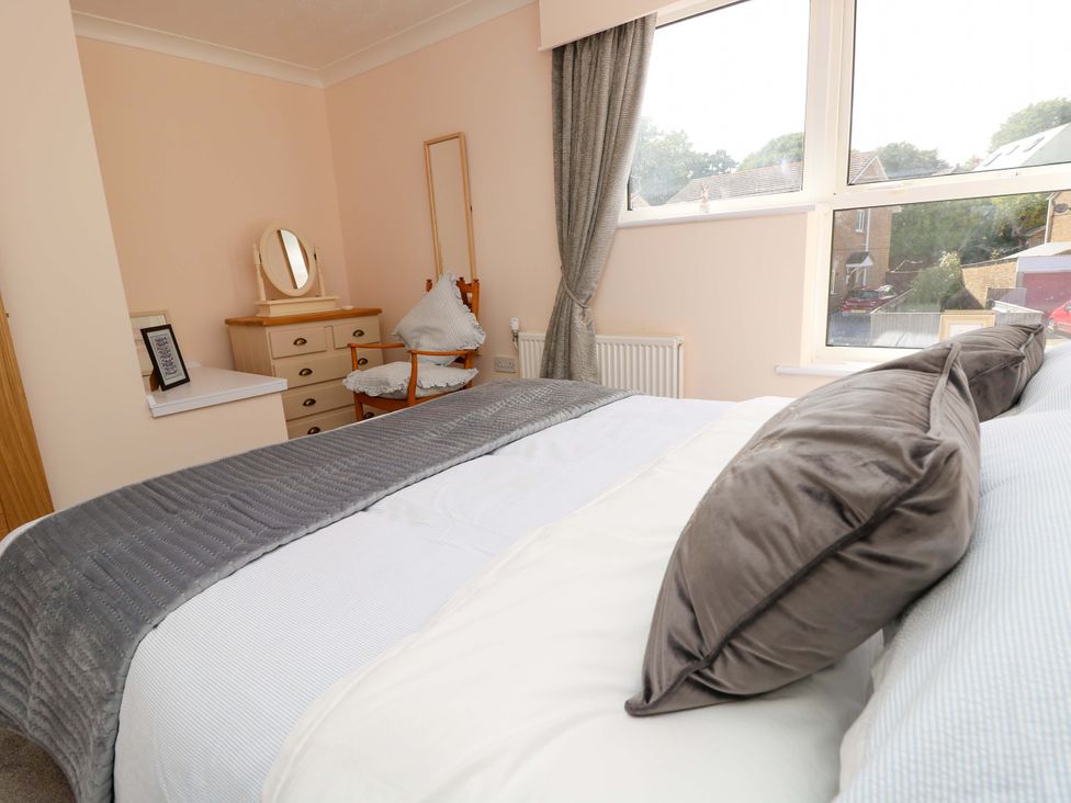 A bedroom with a bed and dressing table at Camellia Cottage in Wimborne Minster