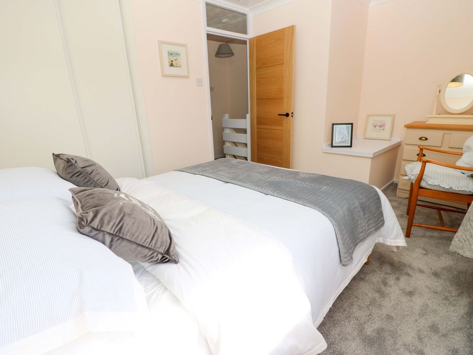 A bedroom with a bed and a mirror at Camellia Cottage in Wimborne Minster