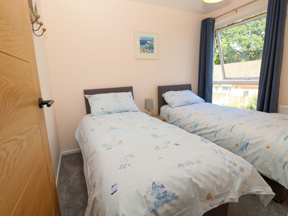 A bedroom with twin beds and a window at Camellia Cottage in Wimborne Minster