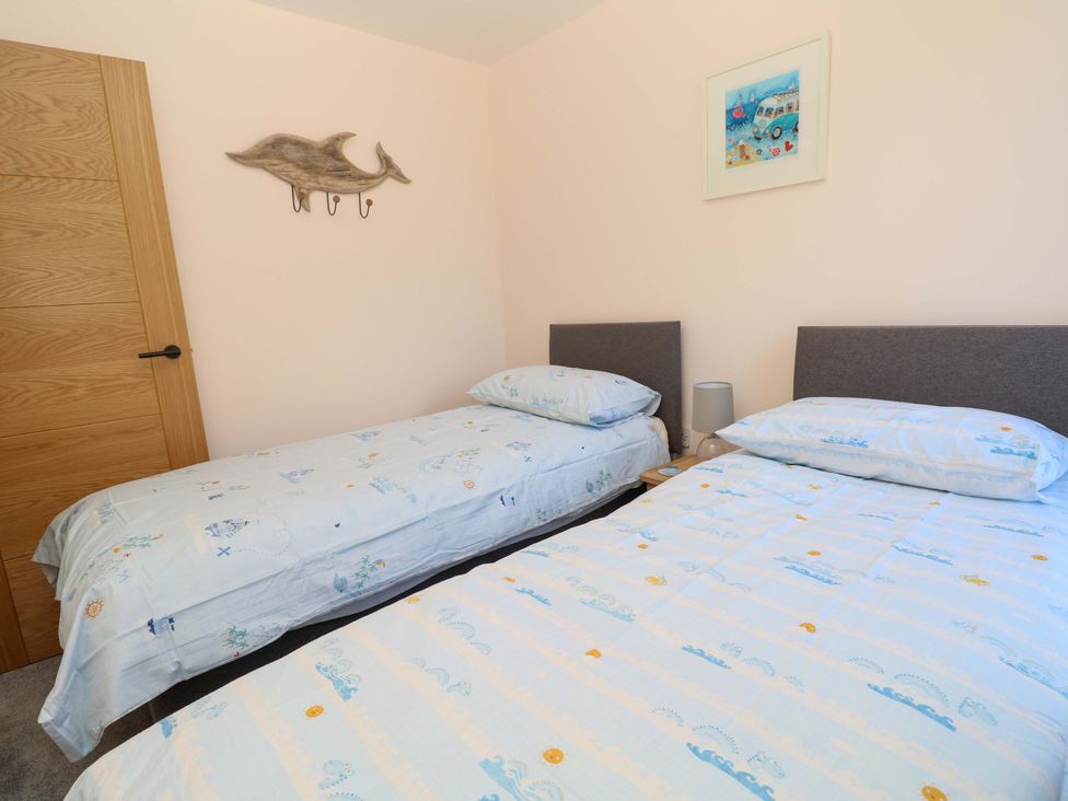 A bedroom with two single beds and wall art at Camellia Cottage in Wimborne Minster