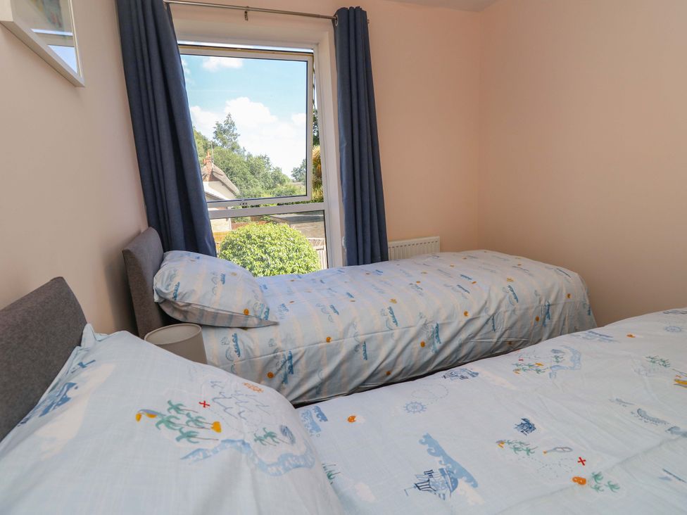 A bedroom with two beds and a window at Camellia Cottage in Wimborne Minster