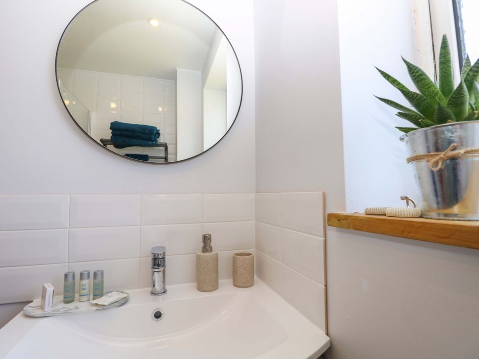 A bathroom with a sink and mirror at Camellia Cottage in Wimborne Minster