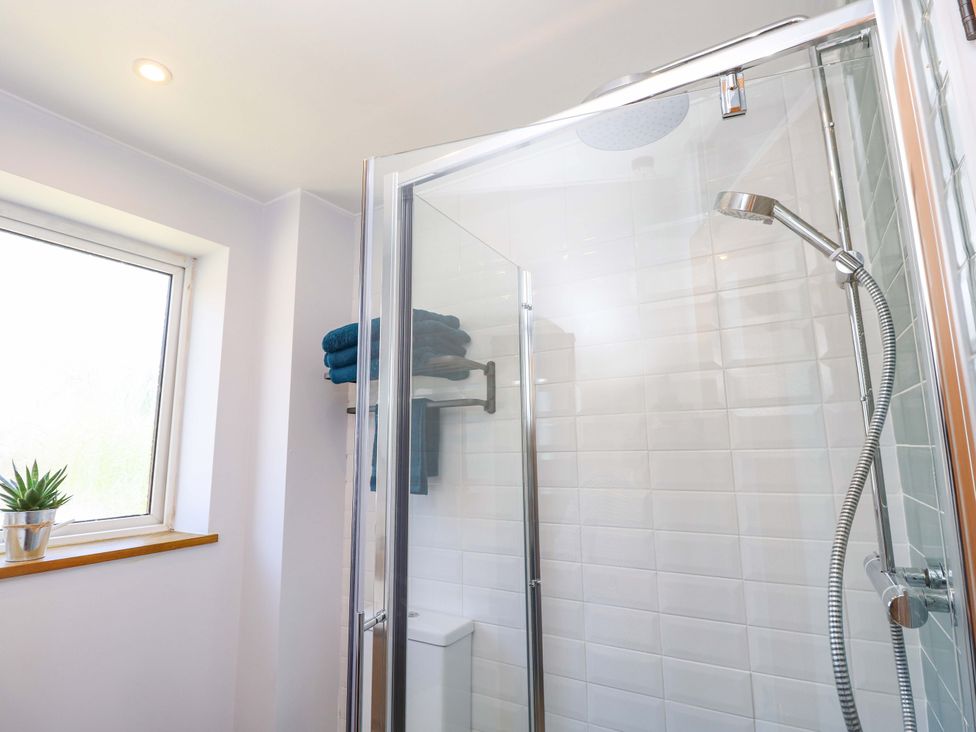 A shower with towels and a window at Camellia Cottage Wimborne Minster