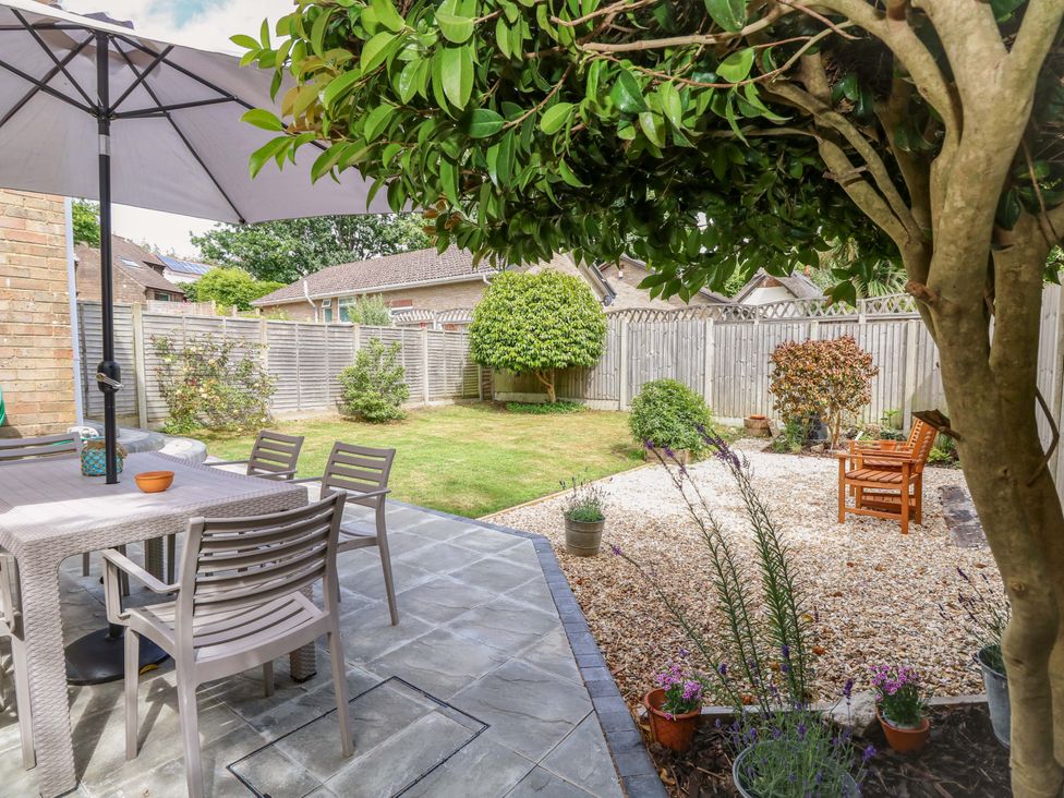 A garden with table and chairs under a parasol at Camellia Cottage in Wimborne Minster