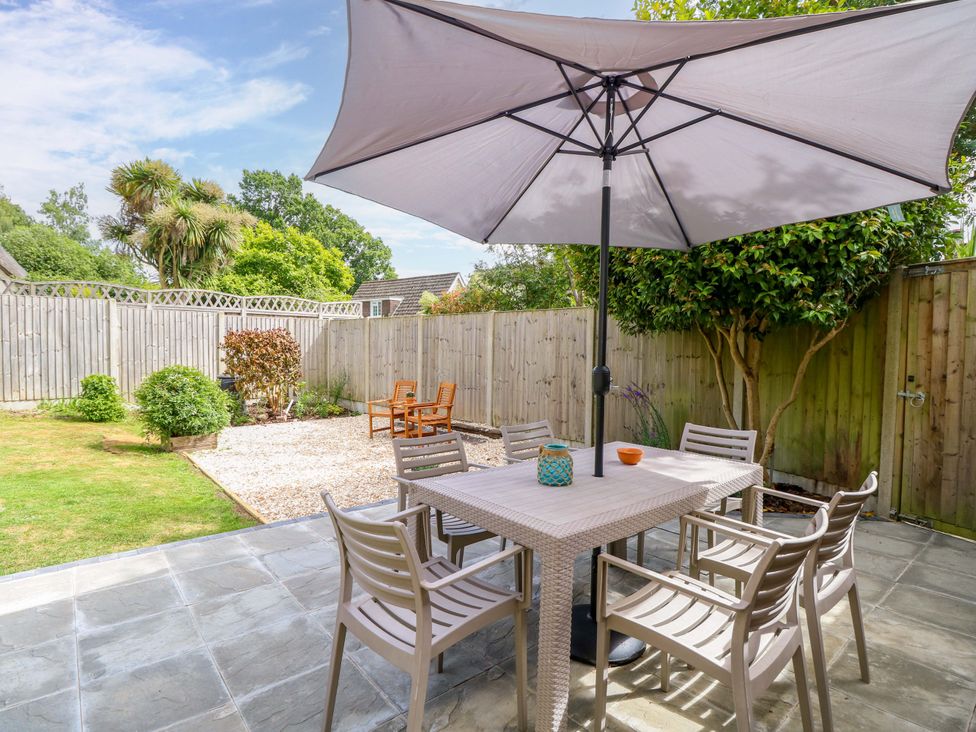 A garden with a table and chairs under an umbrella at Camellia Cottage in Wimborne Minster