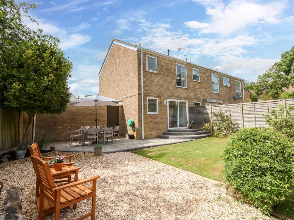 A garden with patio furniture and a house in the background at Camellia Cottage in Wimborne Minster