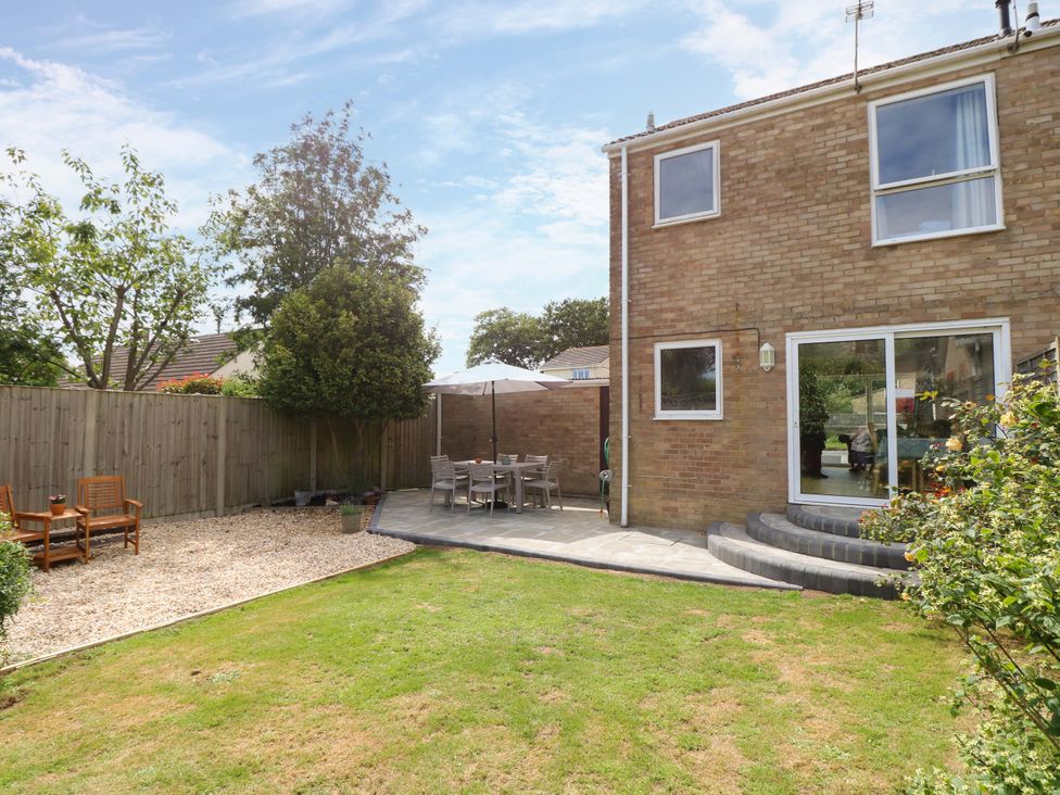 A garden with patio furniture and a house at Camellia Cottage in Wimborne Minster