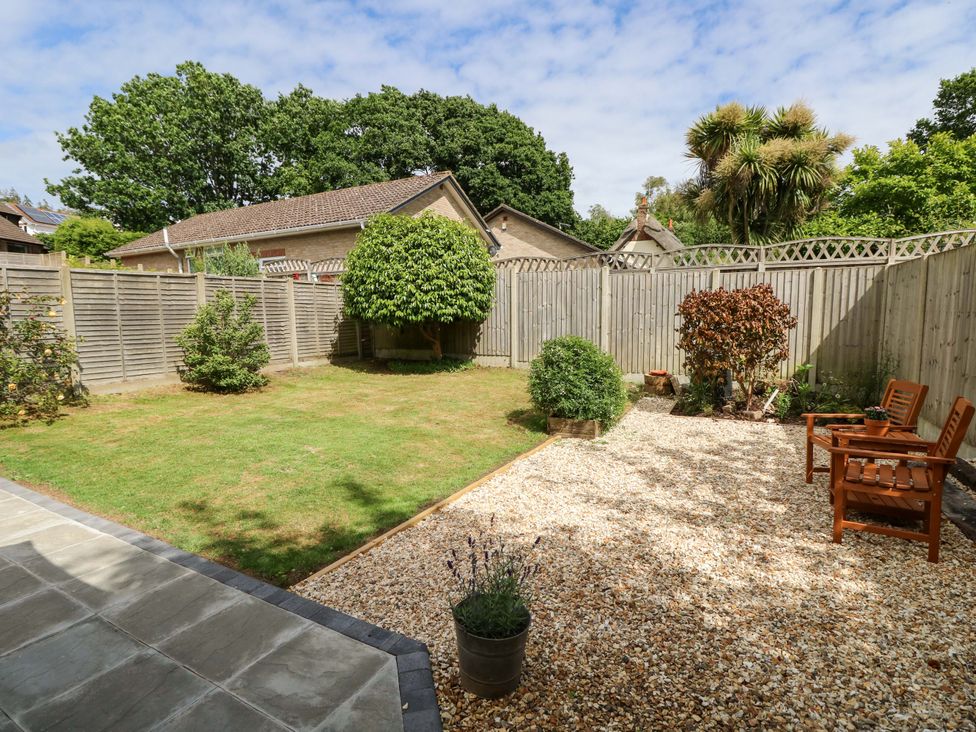 A garden with grass, gravel, and benches at Camellia Cottage in Wimborne Minster