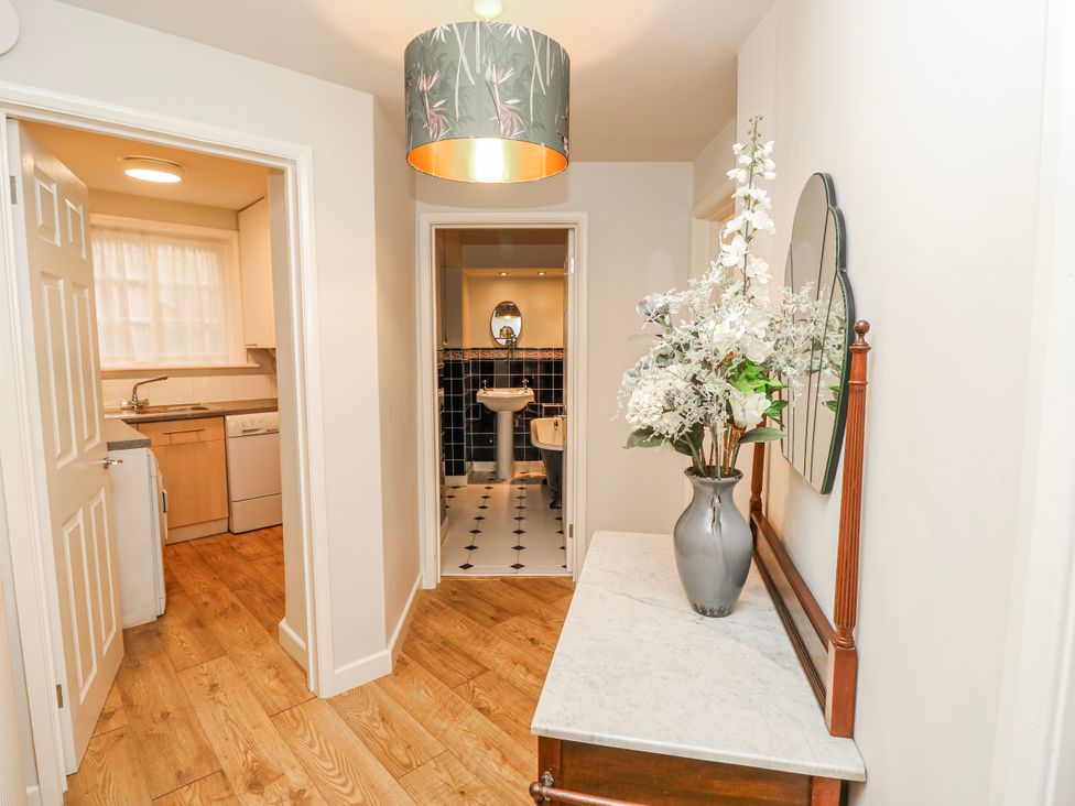 A hallway with a table and flowers leading to a kitchen and bathroom at 1A Clifton Road in Winchester