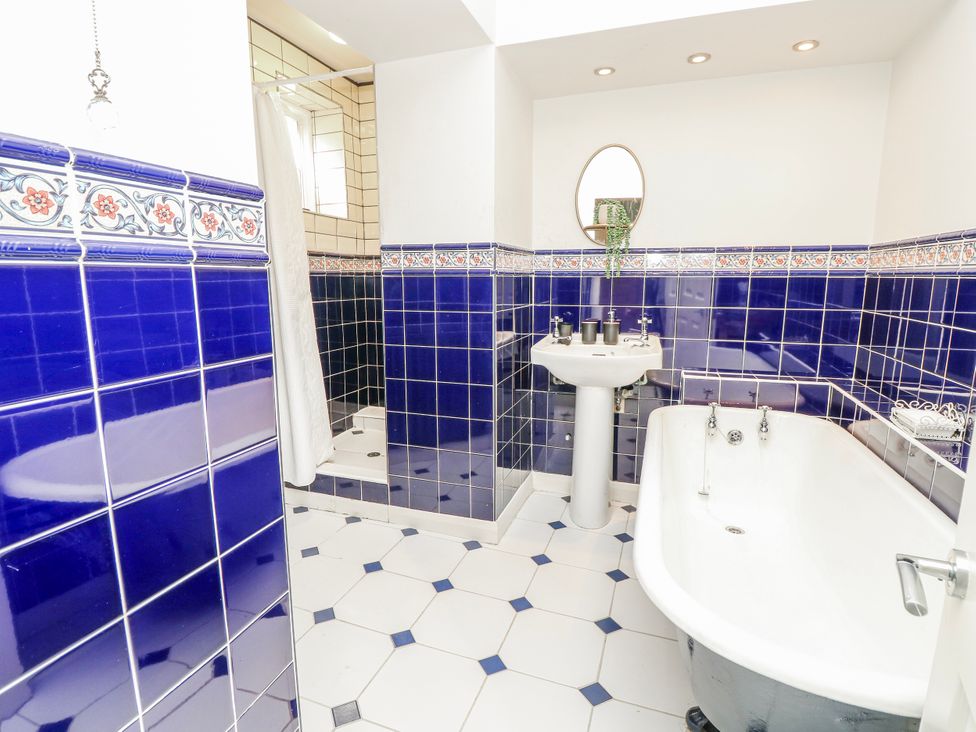 A bathroom with a bathtub, washbasin, and shower at 1A Clifton Road in Winchester