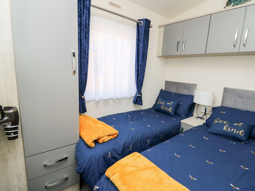 A bedroom with two beds and a window at 33 Woodpecker Lodge in Llanarth