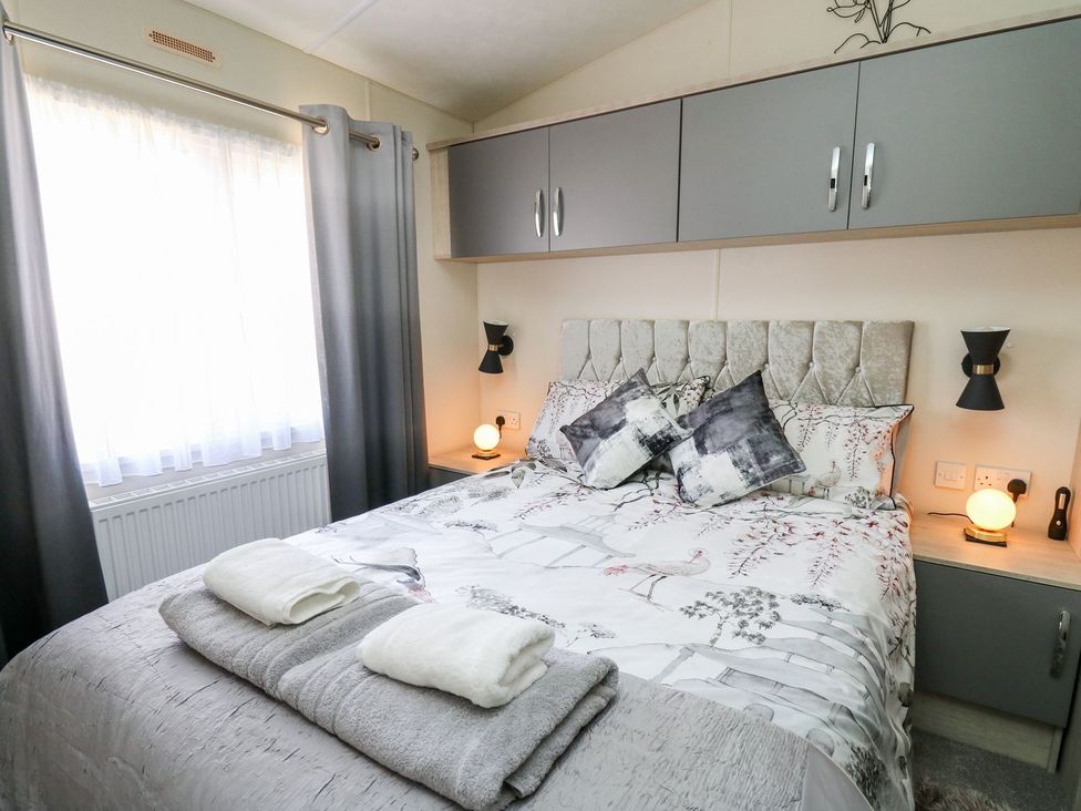 A bedroom with a bed and bedside lamps at 33 Woodpecker Lodge in Llanarth