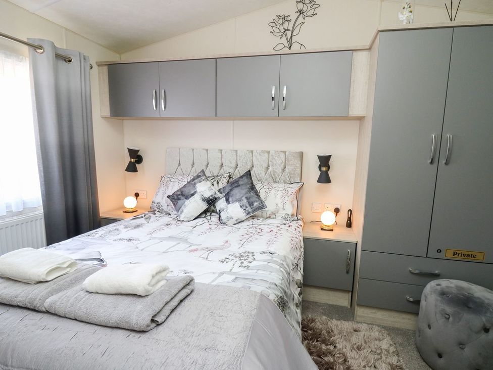 A bedroom with a bed and nightstands at 33 Woodpecker Lodge in Llanarth
