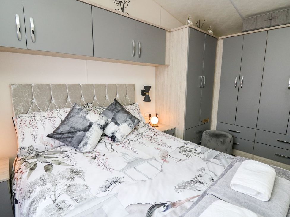 A bedroom with a bed and wardrobe at 33 Woodpecker Lodge in Llanarth